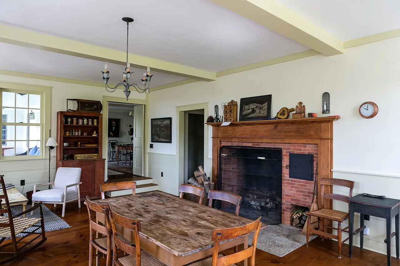 Dining room featuring a rustic wooden table and brick fireplace with wood mantel at Corinth Retreat.