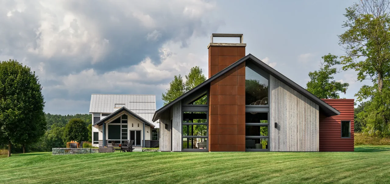 Lake retreat with two buildings showcasing wood siding, metal roof, and large windows by Smith & Vansant Architects.