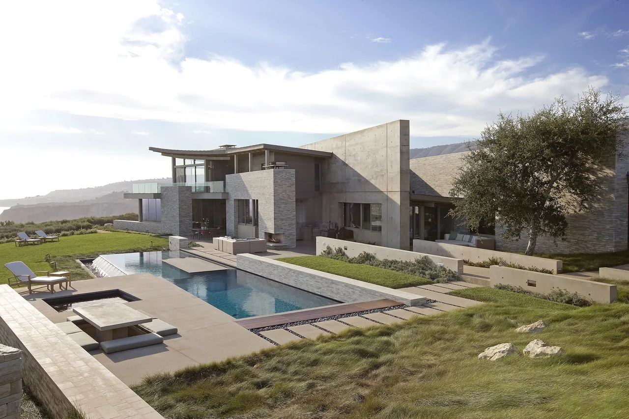 Altamira by Marmol Radziner Architecture features a modern hillside home with a pool and extensive stone and concrete exterior.