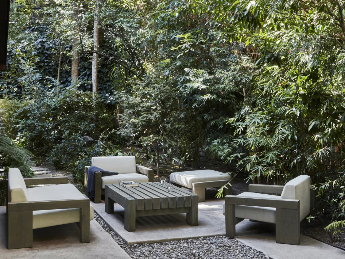 Outdoor living space with modern wood and cushioned seating amidst lush natural landscaping.