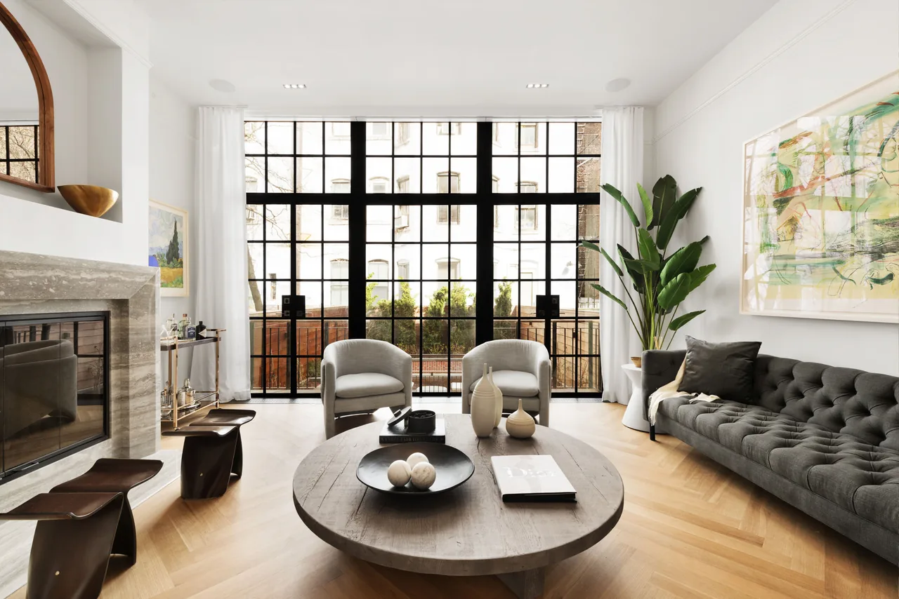 Living room of the West Village Townhouse features large grid-style black window frames and a neutral color palette.