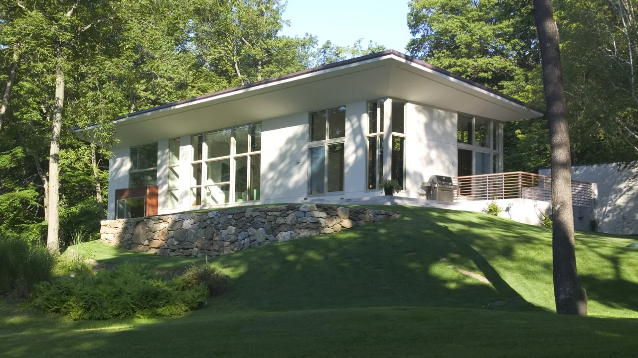 The Pawling Residence features a flat roof with wide overhangs and large windows on a stone foundation.