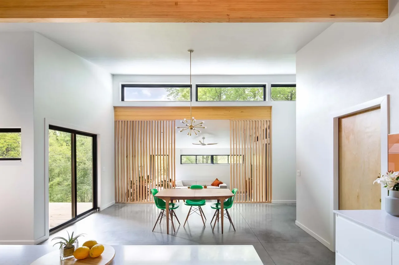 Open dining room features wooden slat divider, green chairs, pendant light, and clerestory windows for natural light.