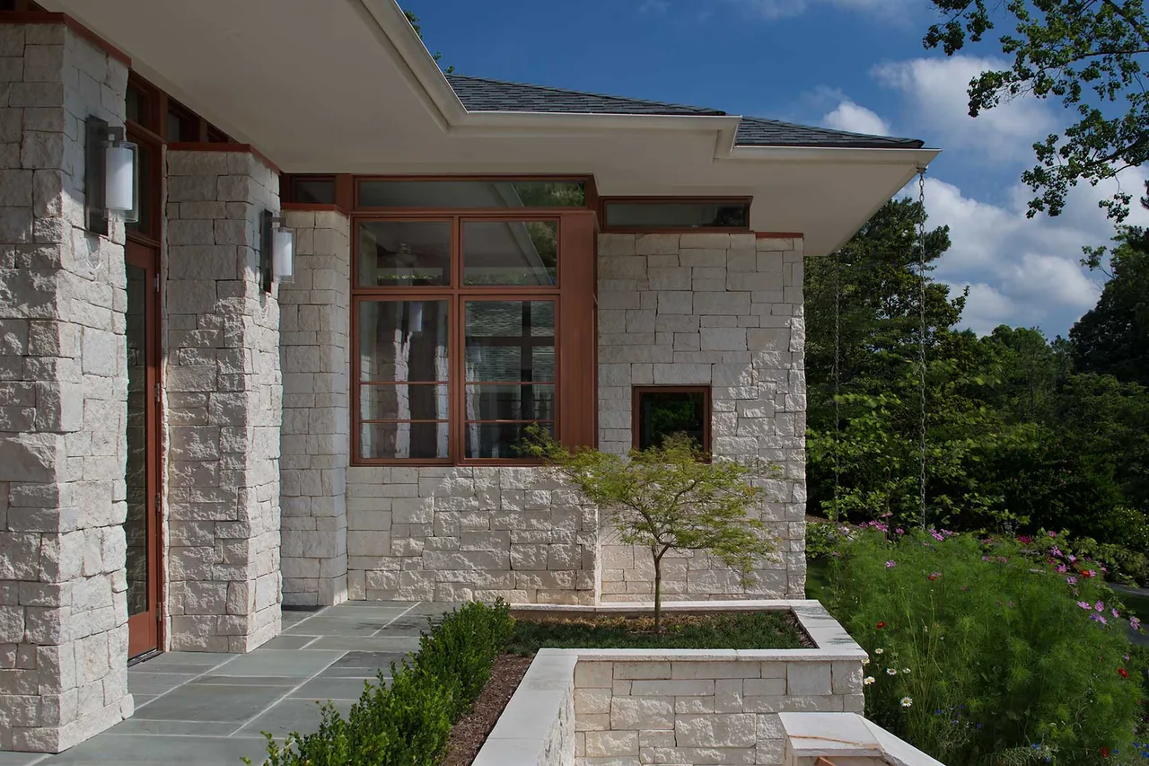 The Kittredge project features stone walls, wood window frames, and multi-level retaining walls with landscaping.