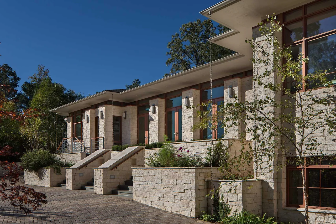 The Kittredge project features a modern exterior with layered stone retaining walls and vertical chain rain diverters.
