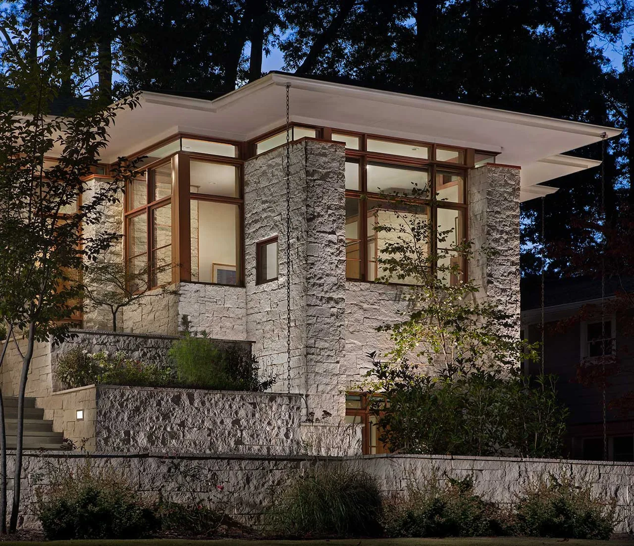 Kittredge project by Studio One Architecture features a modern stone exterior with large windows and a flat roof.