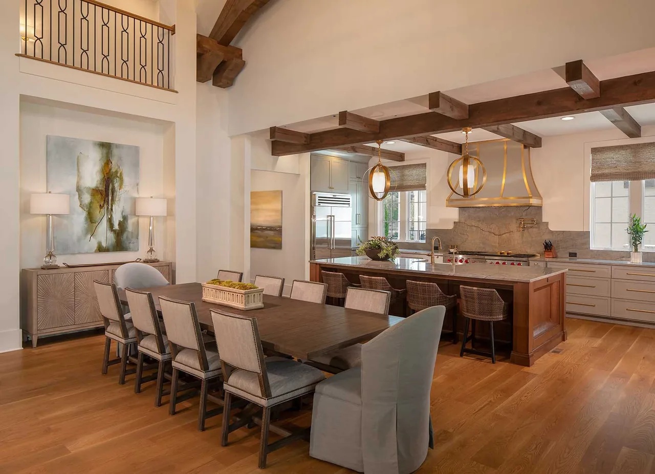 Dining room and kitchen feature light oak floors, exposed wood ceiling beams, and brass pendant lighting over the large island.