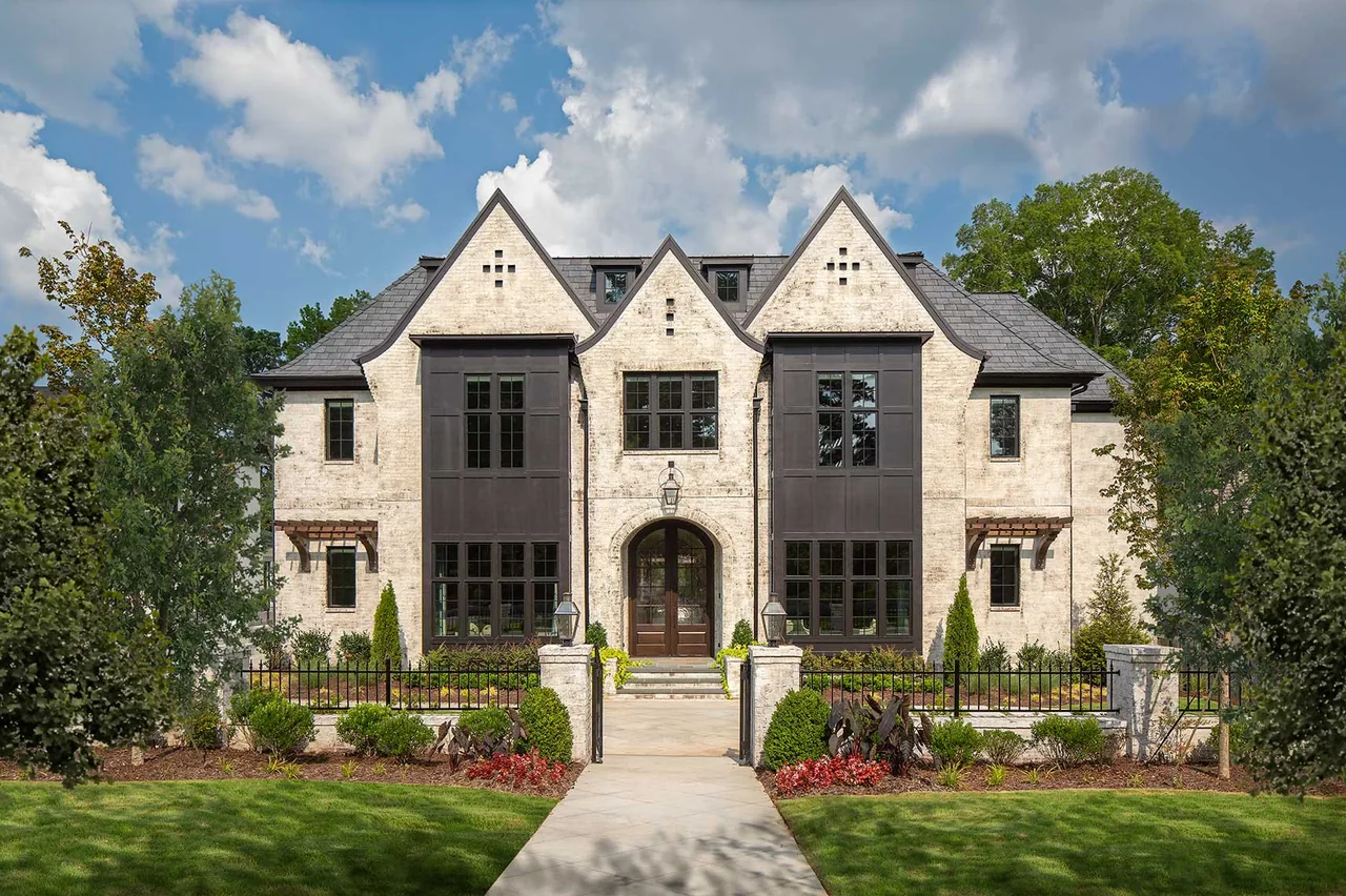 Front view of Haynes Bridge house featuring cream brick exterior and symmetrical gable roofs with black window frames.