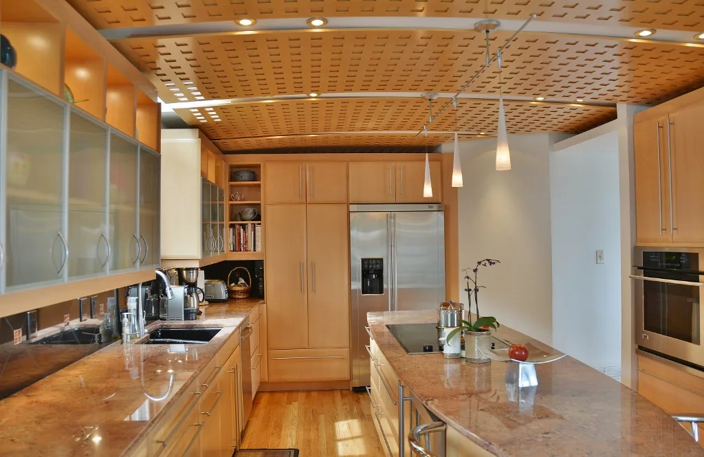 Kitchen featuring light wood cabinets, a unique wood paneled ceiling, and marble countertops with an island cooktop.