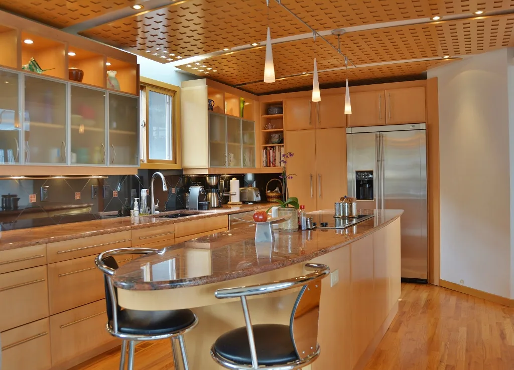 Kitchen in the Silverthorn project features a patterned wood ceiling, granite countertops, and stainless steel refrigerator.