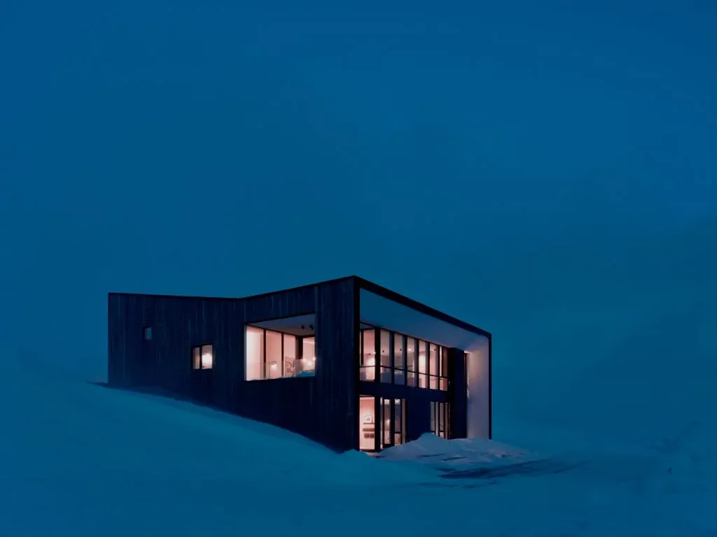 Overlook Cabin by studio ma features a modern design with large floor-to-ceiling windows and dark wood siding.