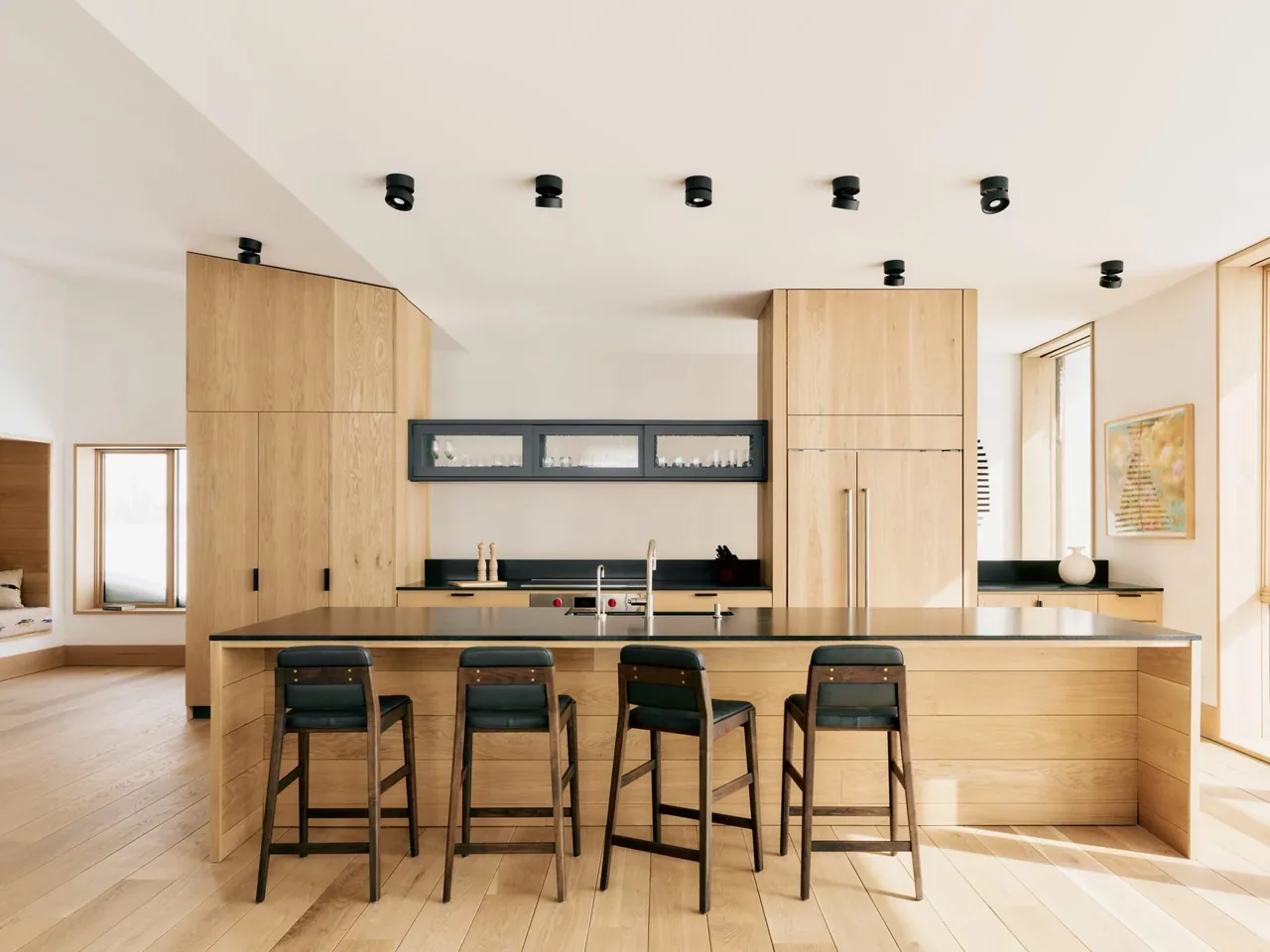Overlook Cabin kitchen with light wood cabinets, a black countertop island, and black ceiling lights.