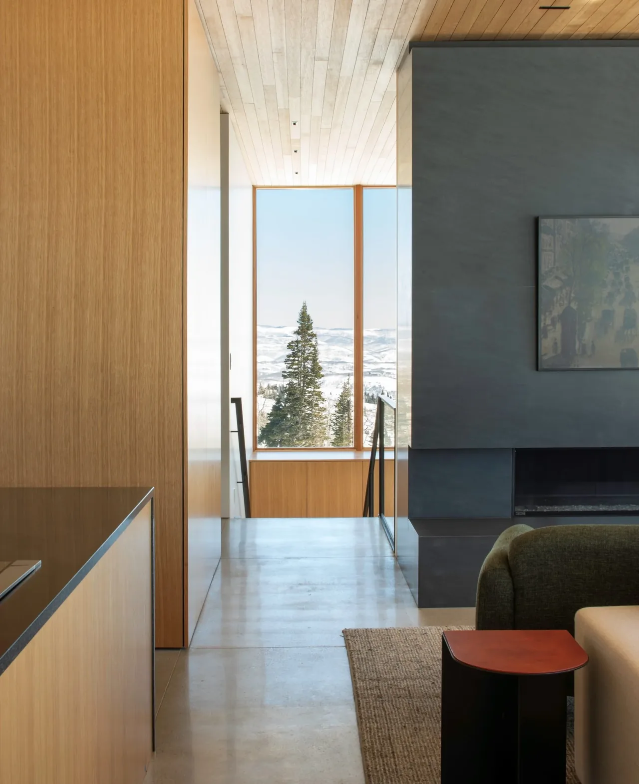 Modern interior hallway leading to a large window with a snowy landscape view.