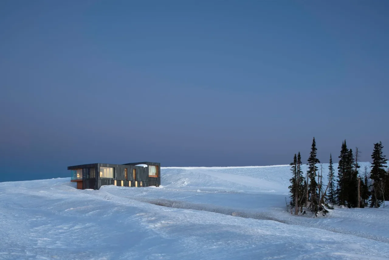 Kirigami project by Sparano Mooney Architecture features dark metal siding and large windows in a snowy setting.