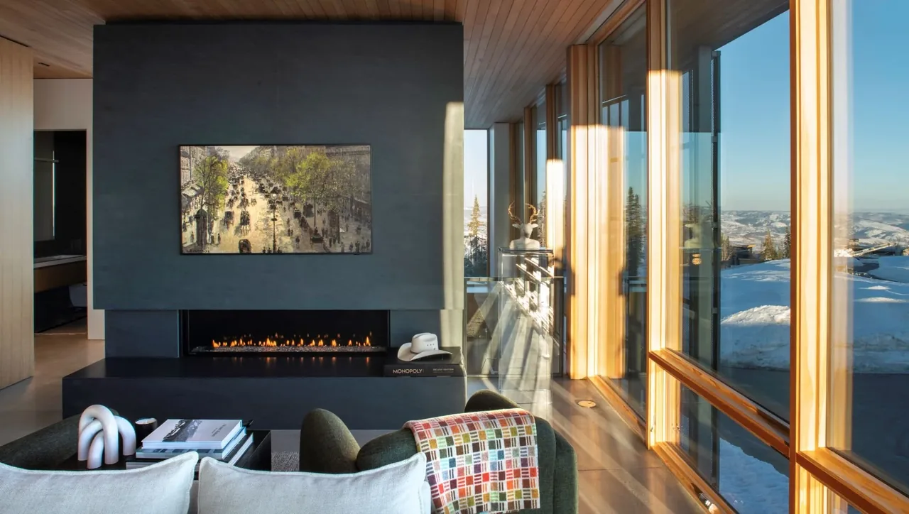 Interior living room with a linear fireplace and floor-to-ceiling wood-framed windows revealing a snowy outdoor scene.