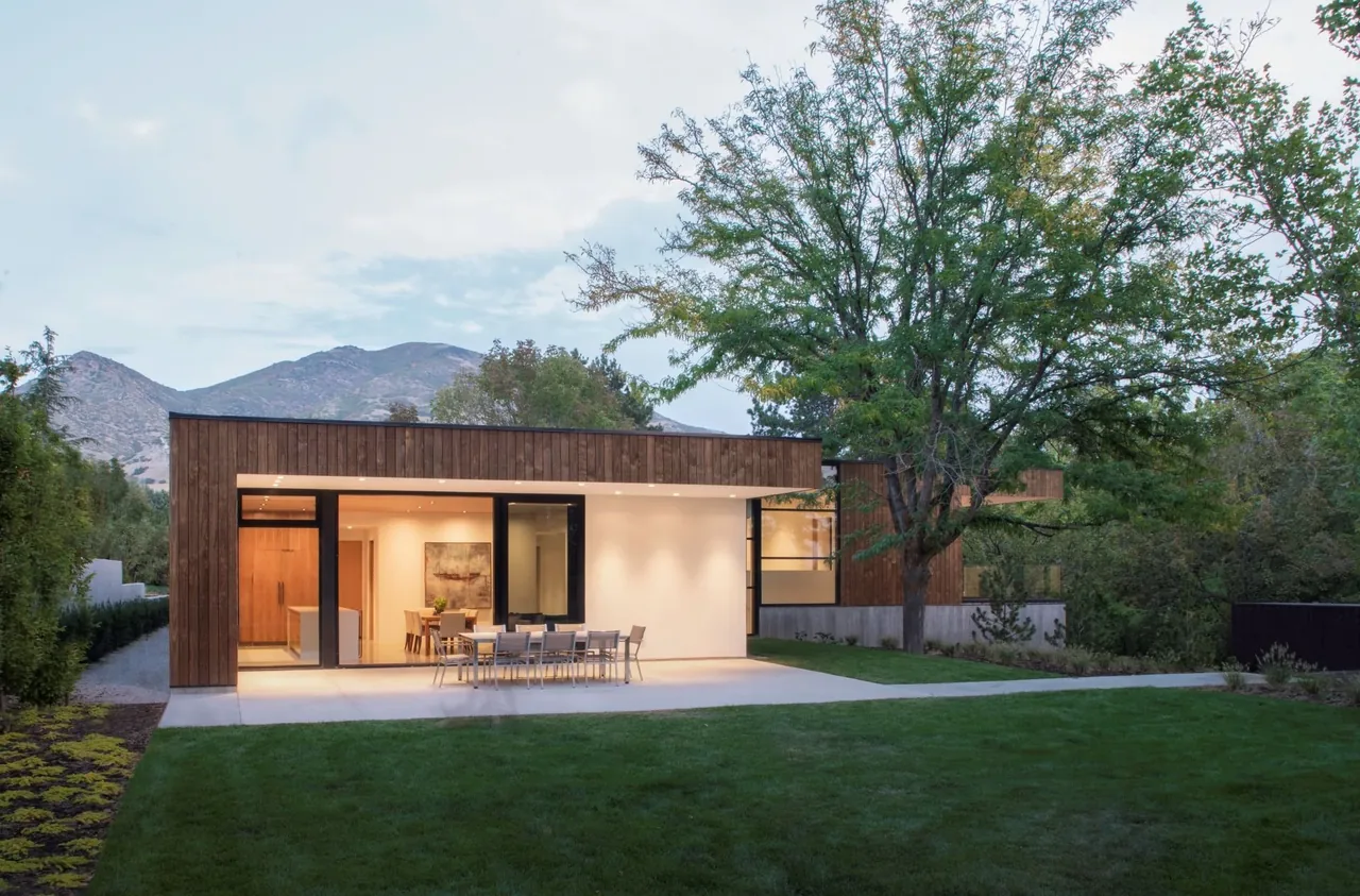 The Emigration Creek Residence features wood siding, large vertical window panes, and a raised front lawn landscape.