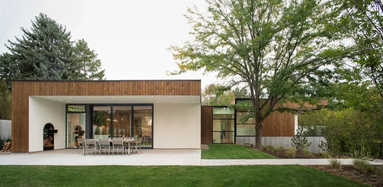 Exterior view of Emigration Creek Residence showing wood siding, large glass doors, and a patio with dining table and chairs.