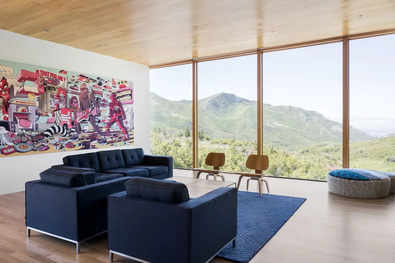Living room with floor-to-ceiling glazing offers panoramic hilltop mountain views and modern furnishings.