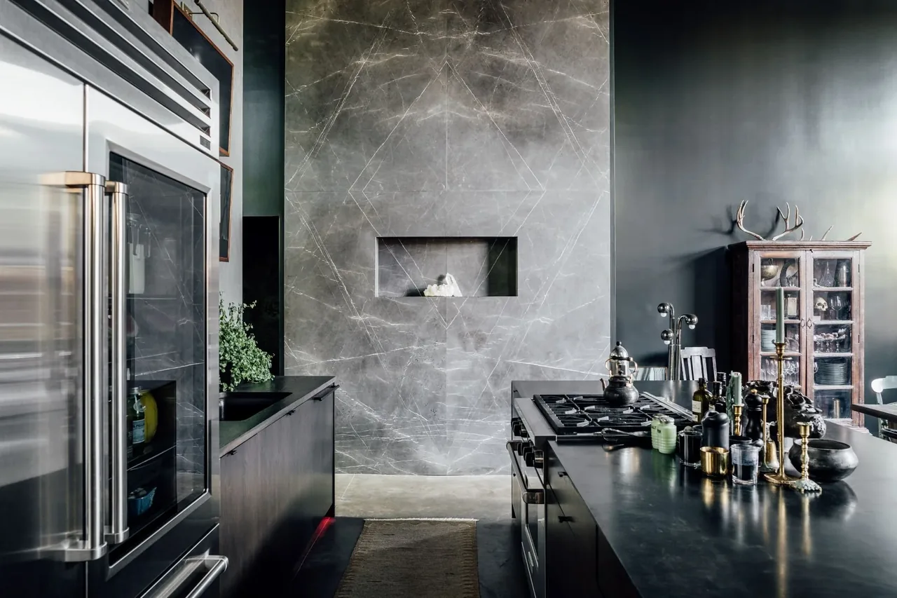 Modern kitchen with dark cabinetry, stainless steel appliances, and a marble fireplace feature wall.