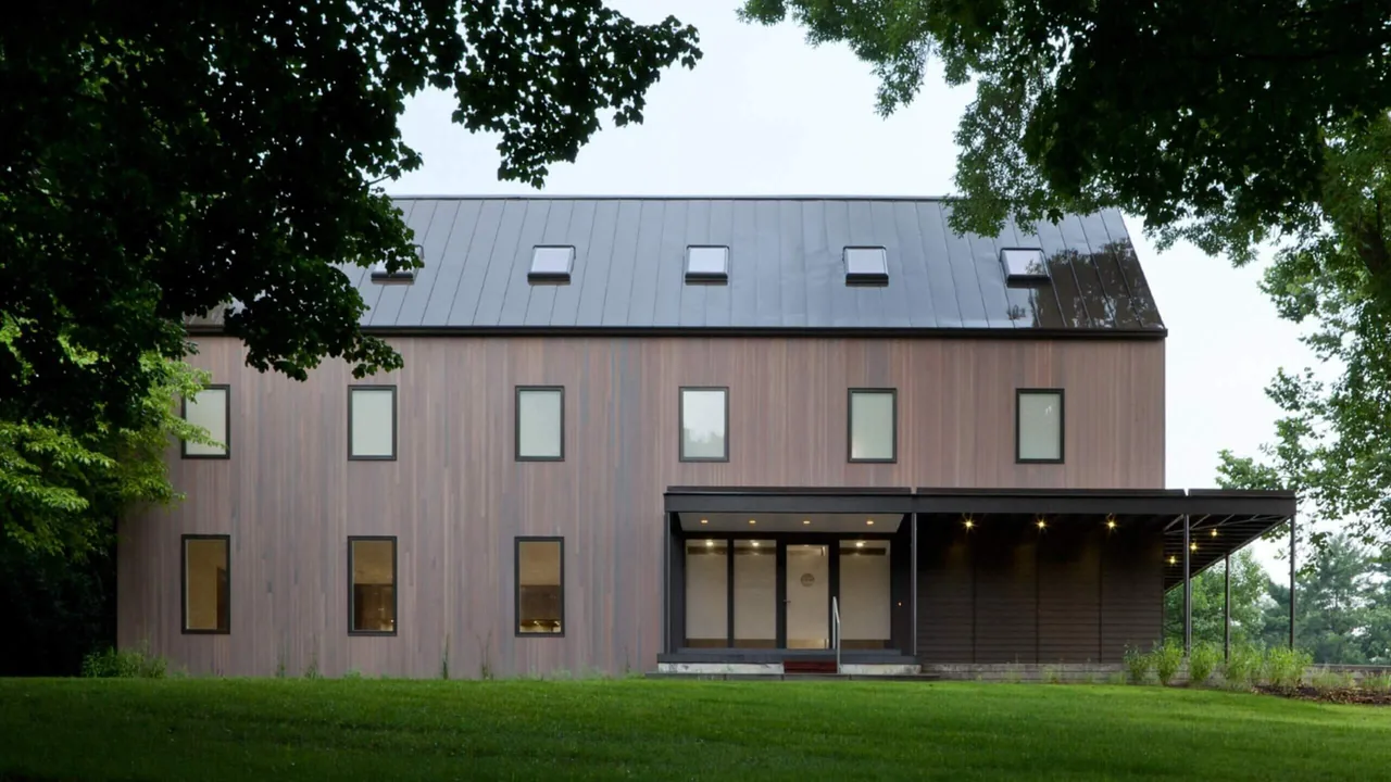 322 Reinvented features vertical wood siding, a standing seam metal gable roof with skylights, and a covered patio with recessed lighting.