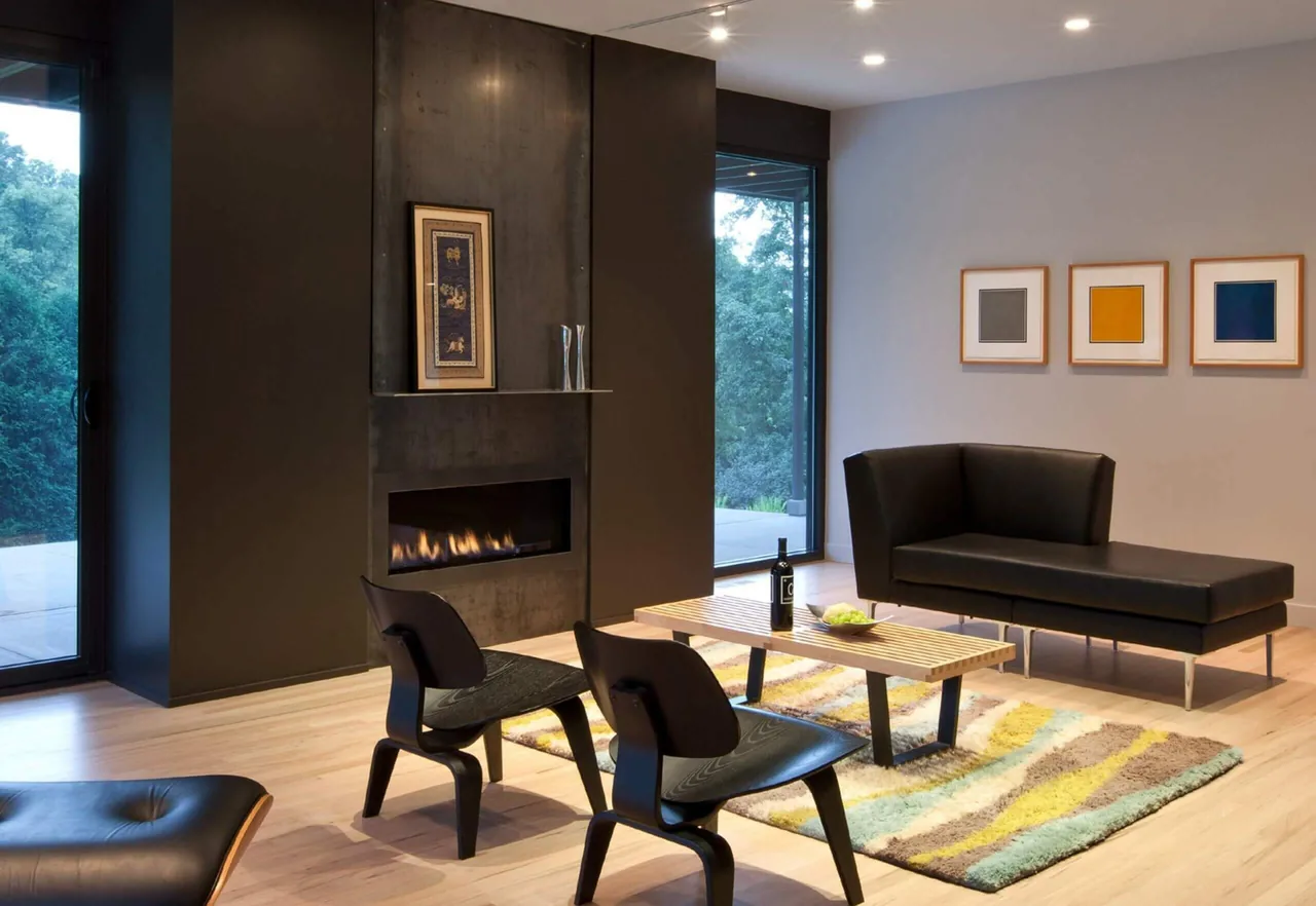 Living room features a black modern fireplace, black seating, wood floors, and large glass doors opening to an outdoor area.