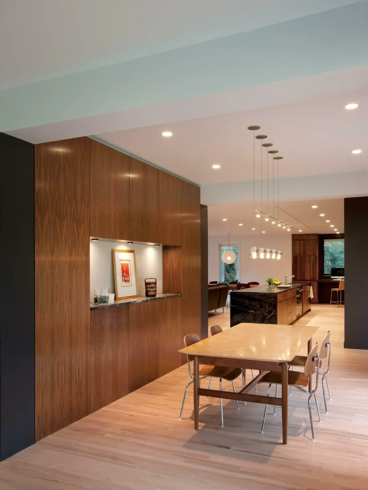 Open dining and kitchen area featuring wood cabinetry and a black marble kitchen island under recessed and pendant lighting.