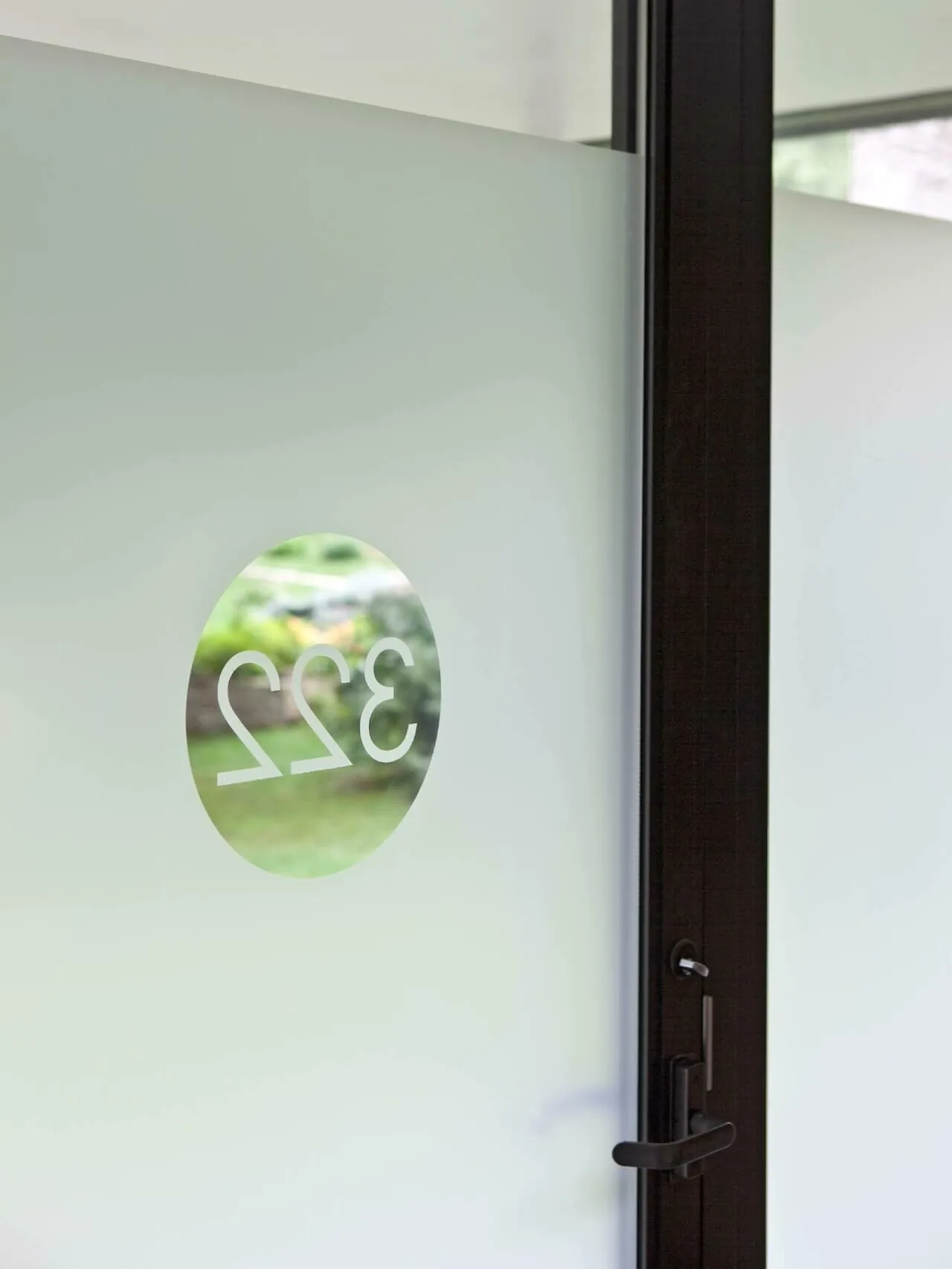 Glass door with black frame and frosted glass, featuring a circular clear window with reversed address number 322.