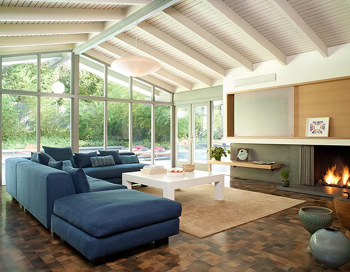 The living area of Canon Residence features floor-to-ceiling glazing, exposed beams, and a modern fireplace.
