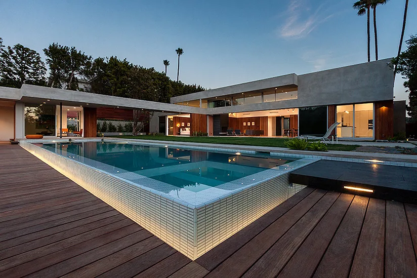 The Arby Residence features a sleek two-story design with a lit pool and extensive wood decking, emphasizing modern architectural elements.