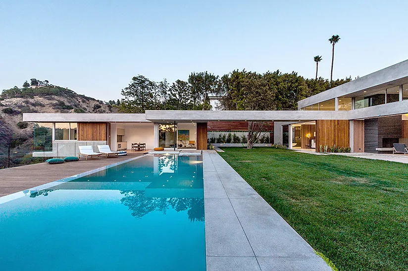 The Arby Residence features a modern two-story design with a rectangular pool, attached spa area, and landscaped backyard with wood decking.