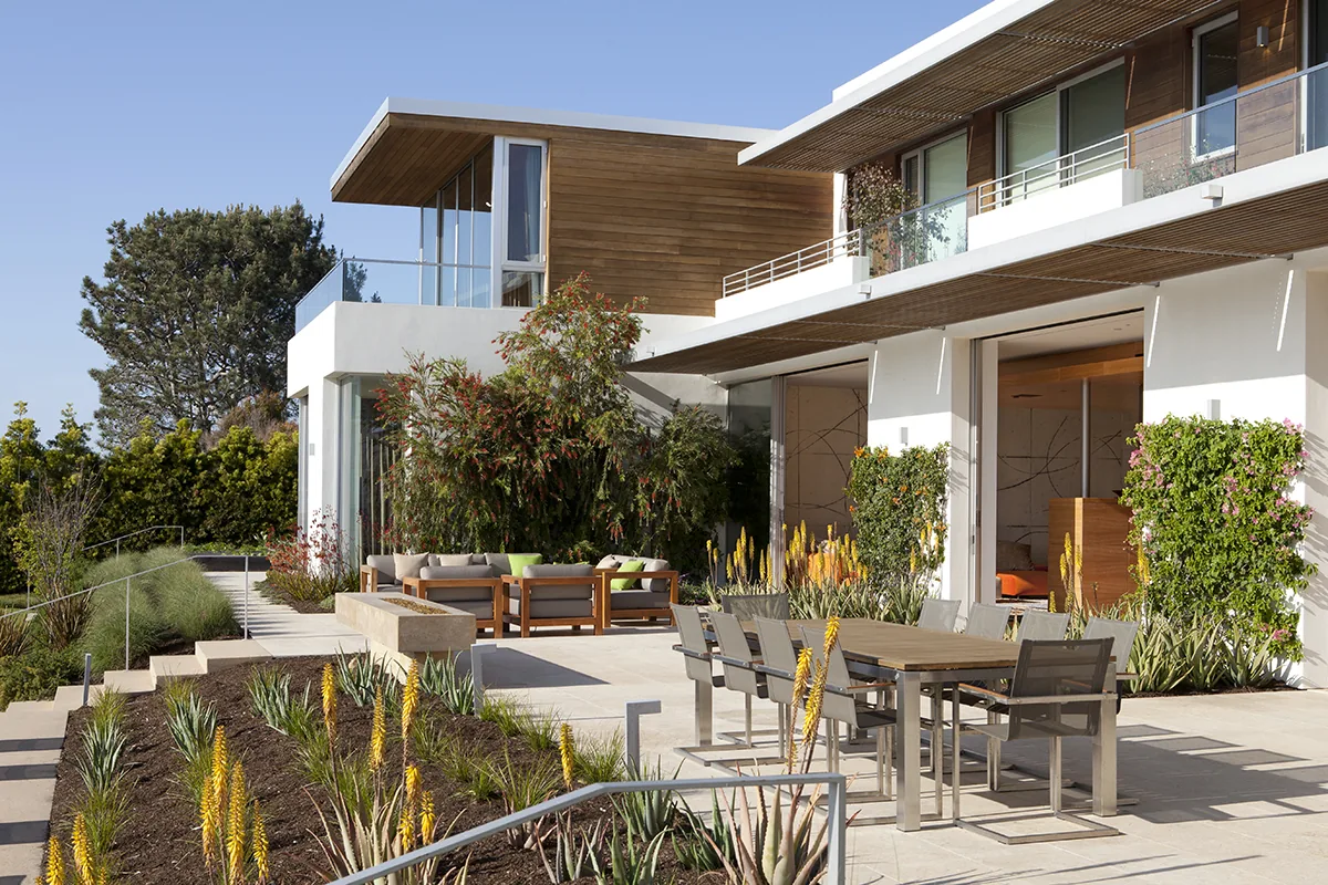 Observatory House features an outdoor patio with dining seating and lounge area surrounded by plants and modern design elements.