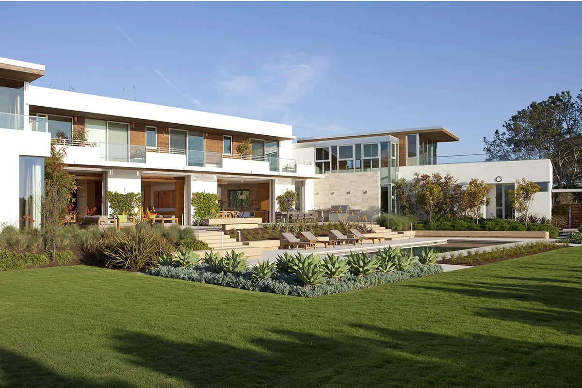 Observatory House features flat roofs and extensive glazing with a large landscaped lawn and outdoor seating area.