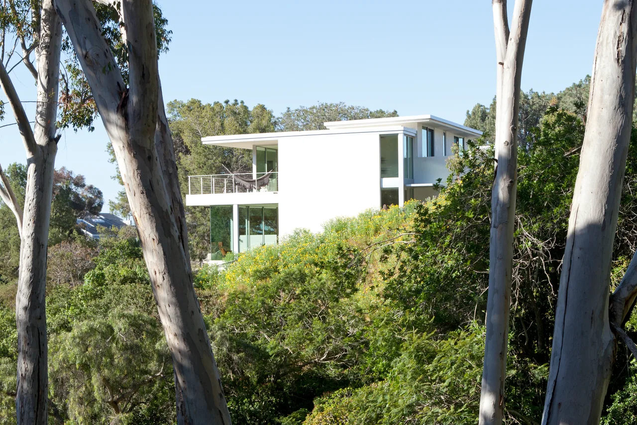 Clark Street Private Residences features a modern hillside home with extensive glazing and a balcony with glass railing.