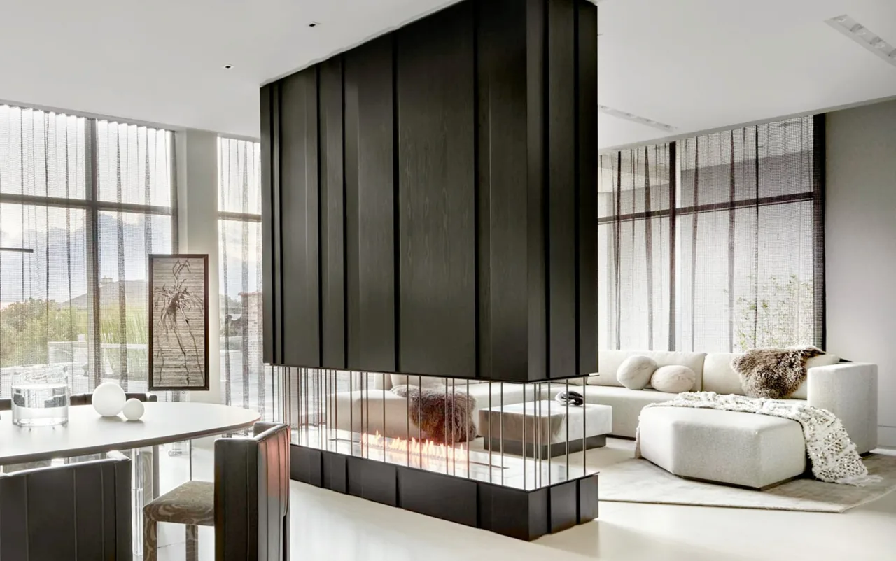 The Art House living room features a suspended fireplace with black paneling and sheer window curtains throughout.