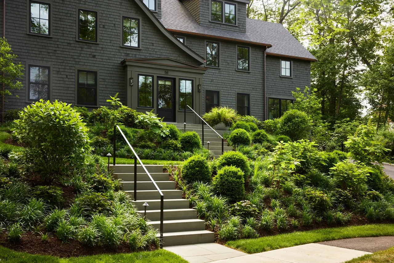 Valentine House features a gray shingle exterior with dormer windows and a landscaped garden at the entry stairway.