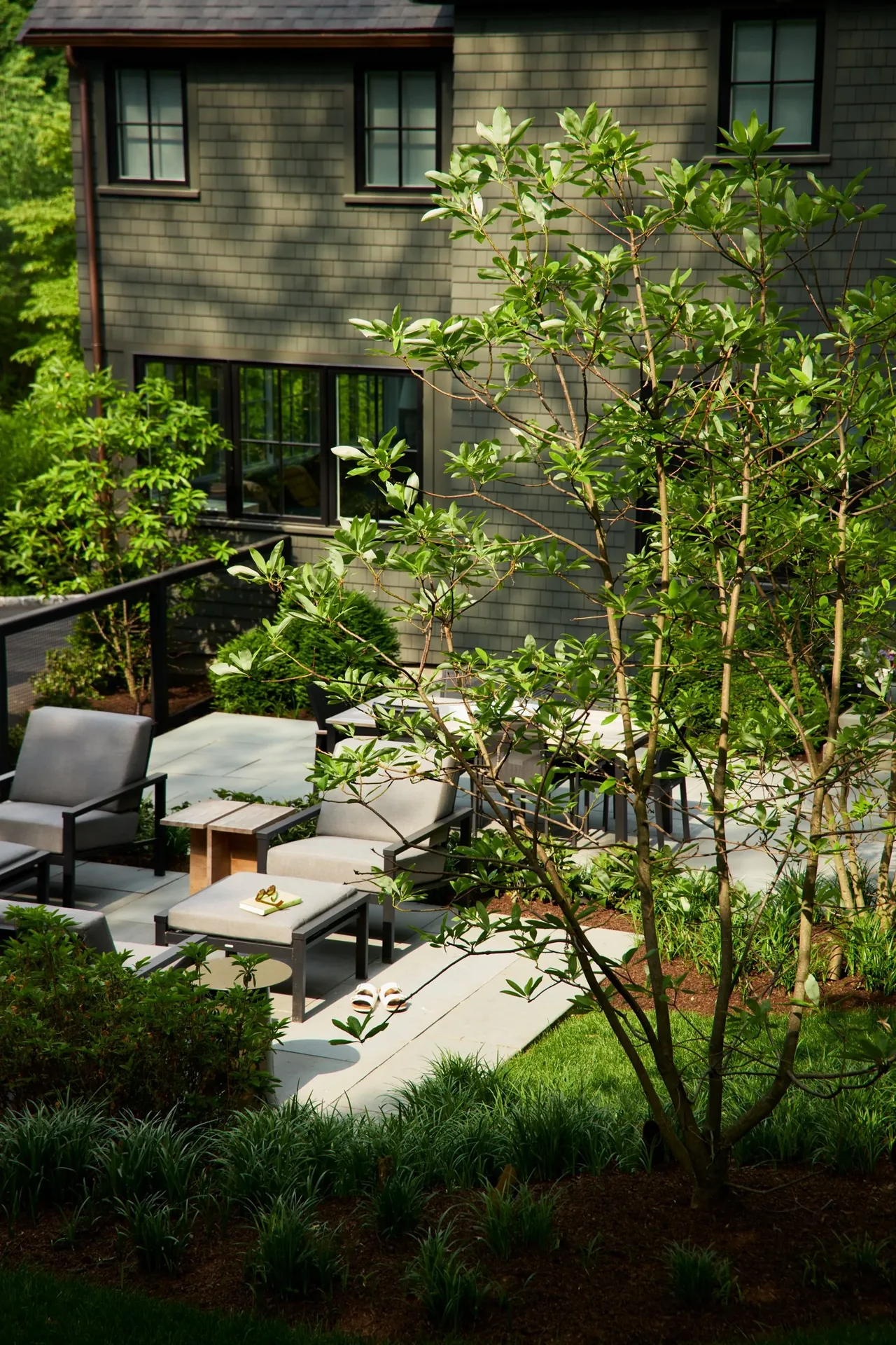The Valentine House features black window frames and a landscaped garden with a patio seating area.