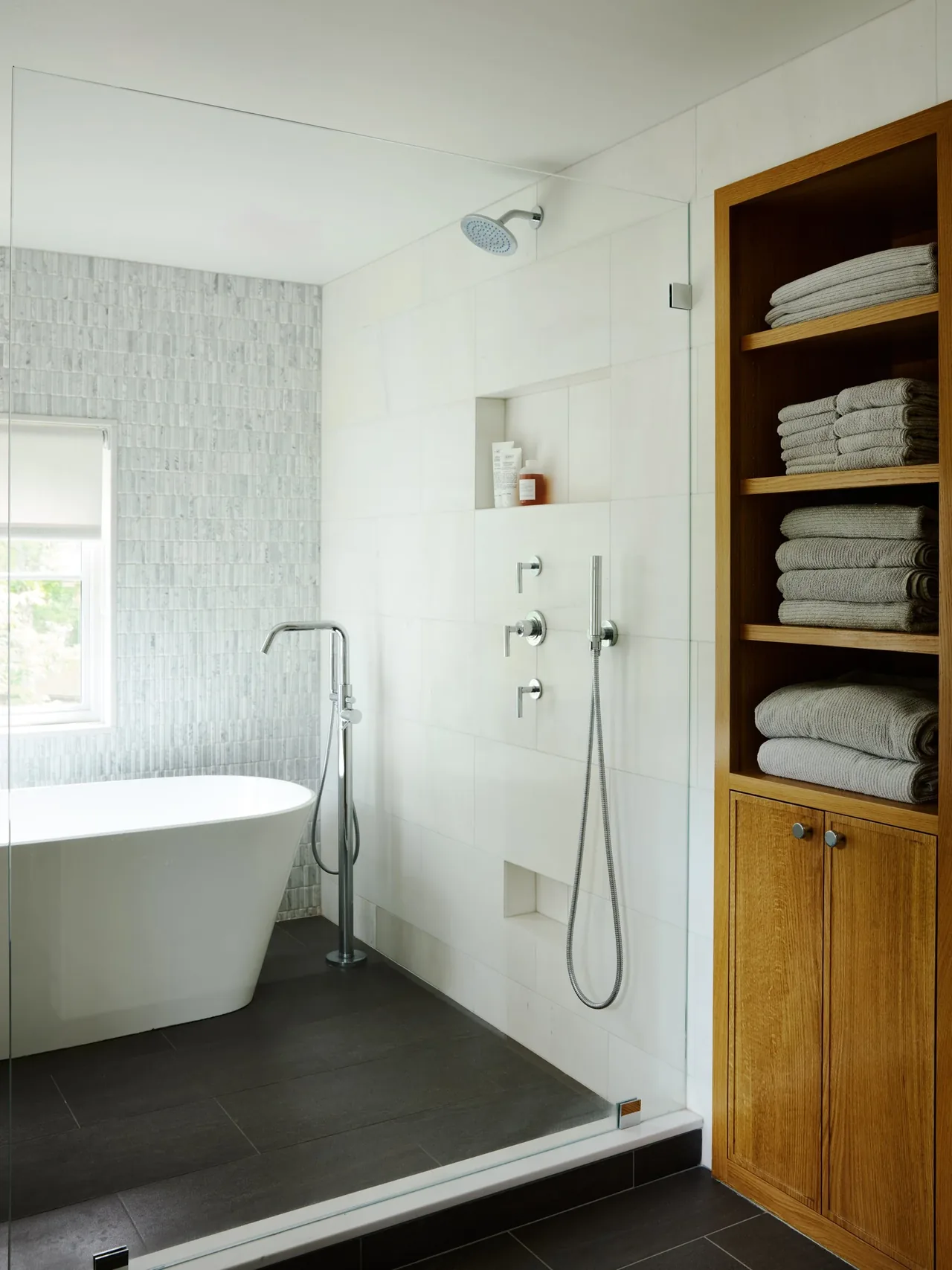 Bathroom with freestanding bathtub, walk-in shower, and wooden towel shelving.