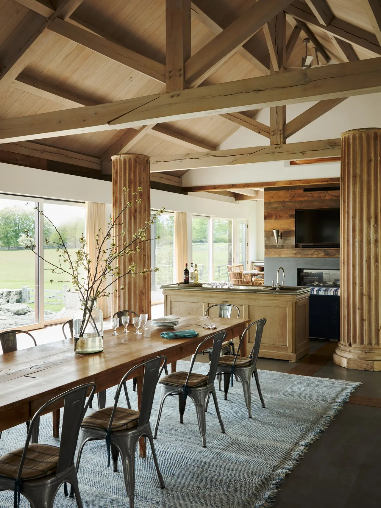Dining room at Westport House with a wooden table, metal chairs, vaulted ceiling, and large windows offering a countryside view.