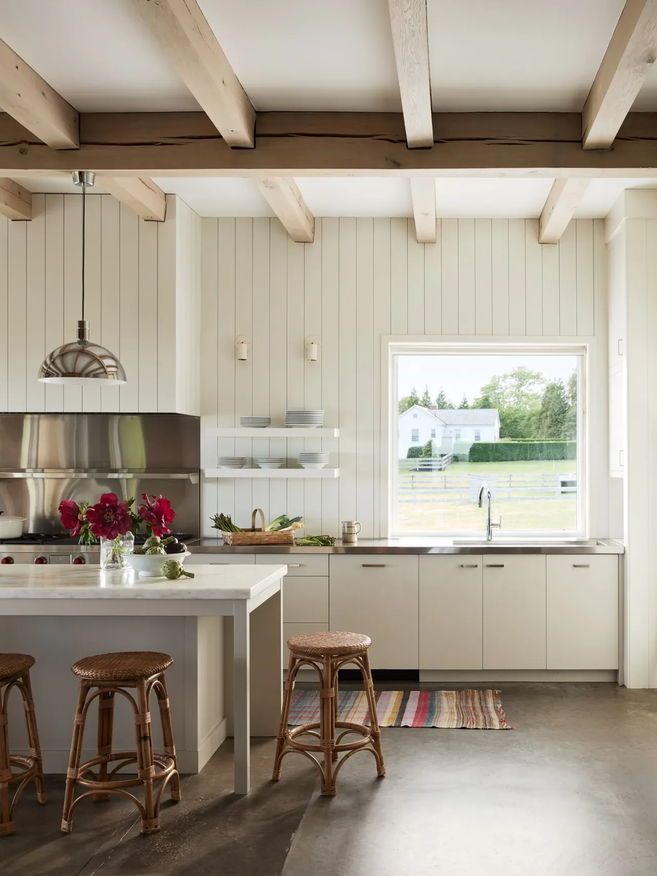 Kitchen with exposed wood beams, a large window, and a central island with wicker stools at the Westport House project.