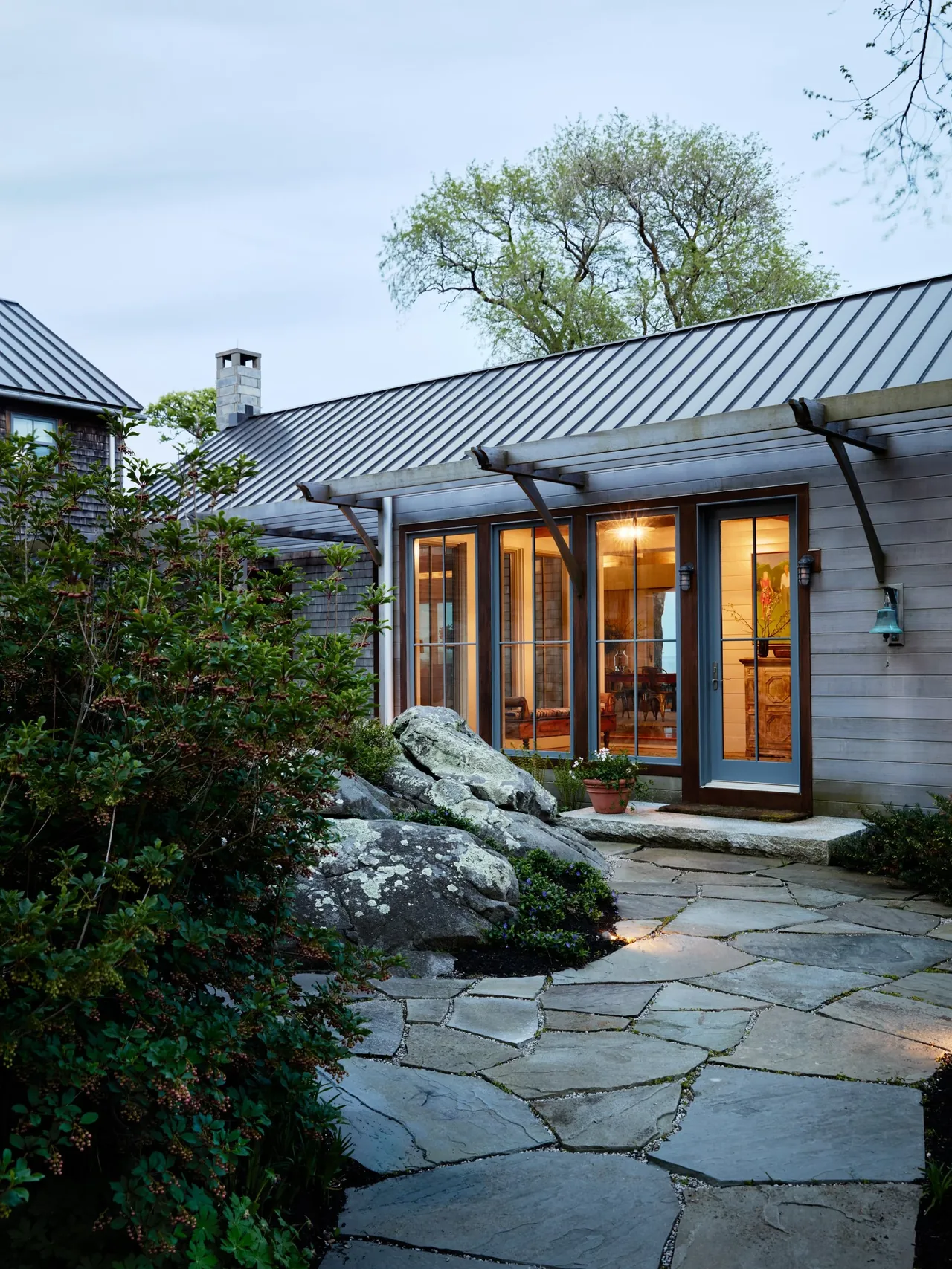 Rear exterior entry of Westport House features stone paving and standing seam metal roof.