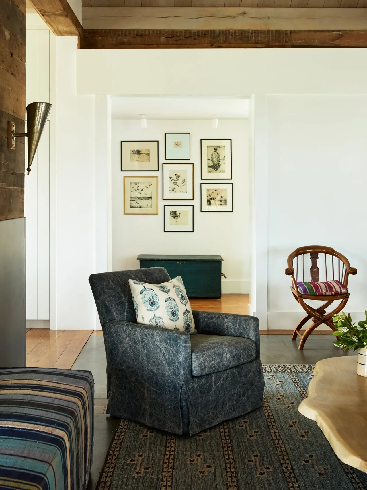 A cozy living space featuring a black upholstered armchair, striped wooden chair, and framed drawings on a white wall at Westport House.
