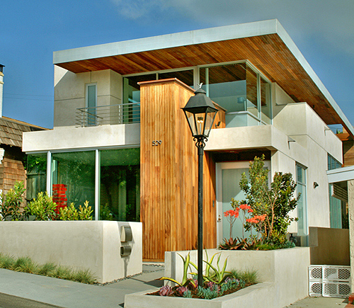 Exterior view of a modern two-story house with white walls, wooden accents, and large glass windows.