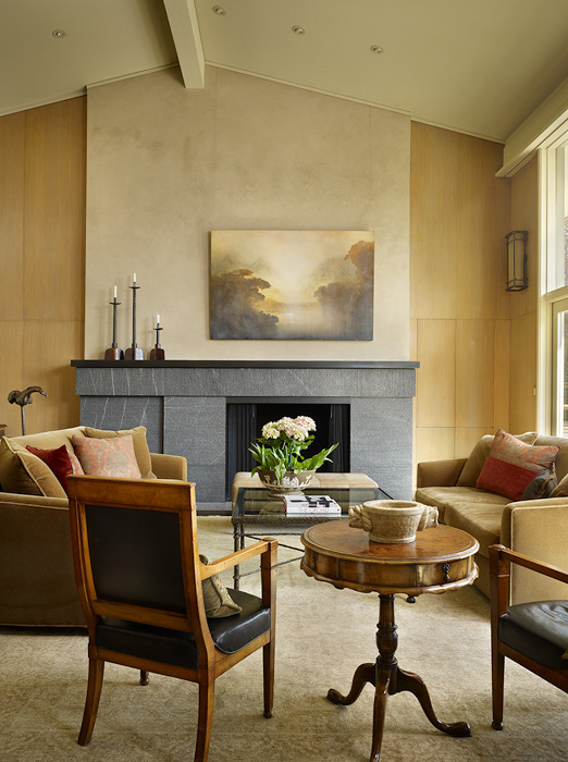 Living room of Haller Lake Residence features a tall gray stone fireplace with light wood panel walls and leather and fabric seating.