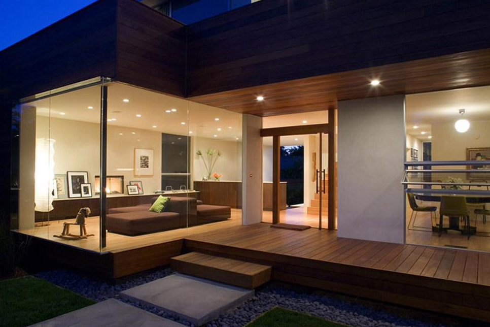 Night view of Ridgewood Residence showing the wood-paneled exterior and illuminated interior through floor-to-ceiling glass windows.