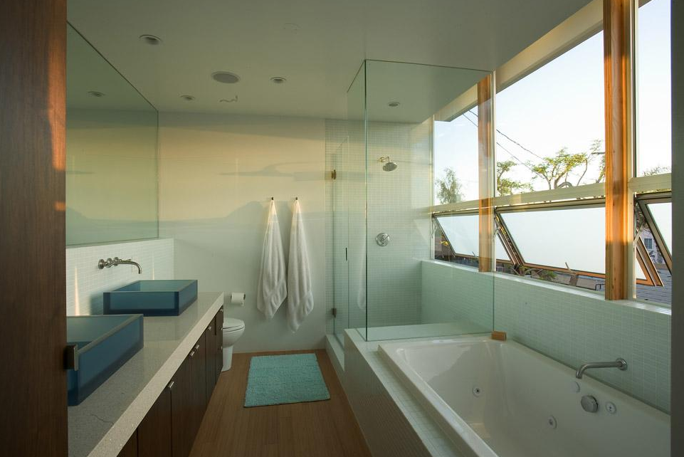 Ridgewood Residence bathroom features glass shower, dual blue vessel sinks, and natural wood flooring designs.