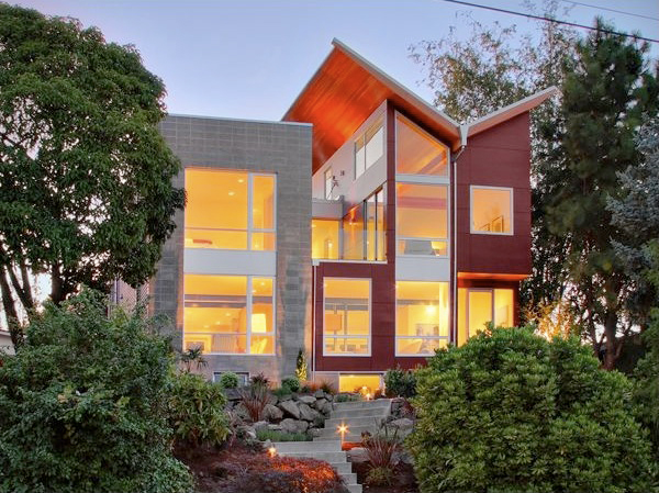 The Queen Anne House features a butterfly roof and extensive glazing, showcasing modern architectural design in a lush setting.