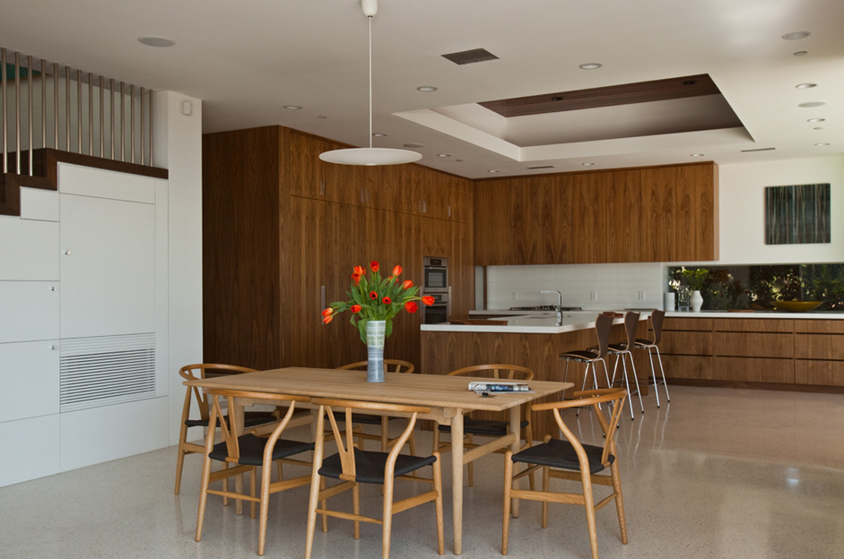 Open kitchen and dining space featuring wood-paneled cabinetry and a wood dining set with modern seating.