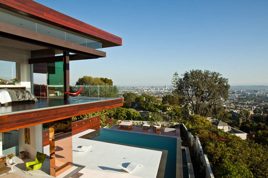 The Sunset Plaza Residence features wood-paneled exterior and a glass-railing balcony overlooking a pool with city views.