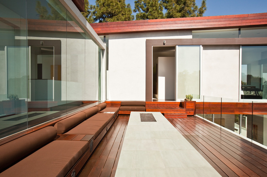 Sunset Plaza Residence features a modern outdoor living space with wood decking, built-in seating, and a fire pit.