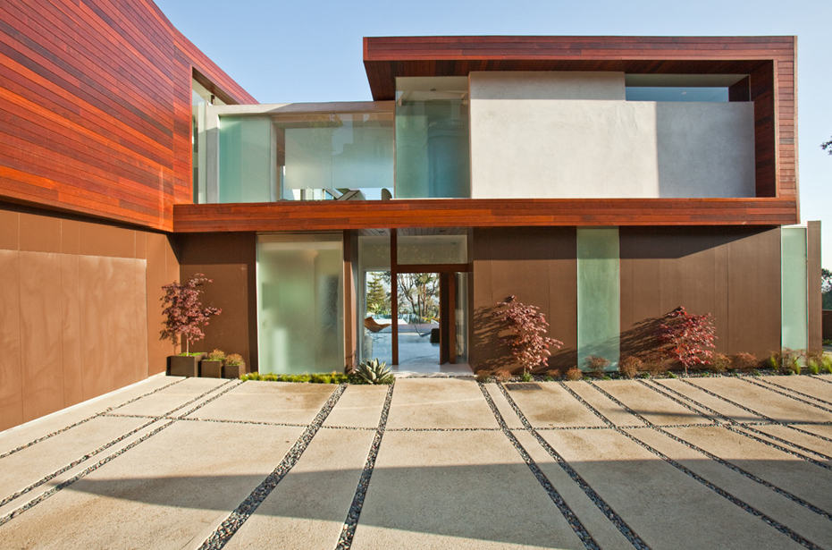 Exterior front view of Sunset Plaza Residence featuring wood siding and large curtain walls by Assembledge Architects.